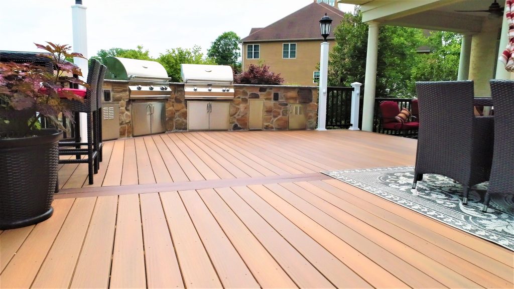 Wide composite deck leading to a stone outdoor kitchen