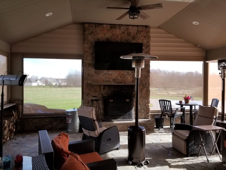 Enclosed outdoor room with a stone fireplace, TV and lounge seating