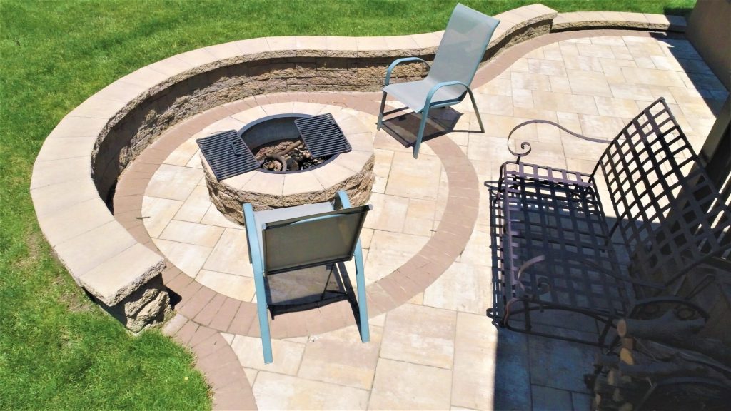 Curved paver patio with a built-in fire pit and seat wall
