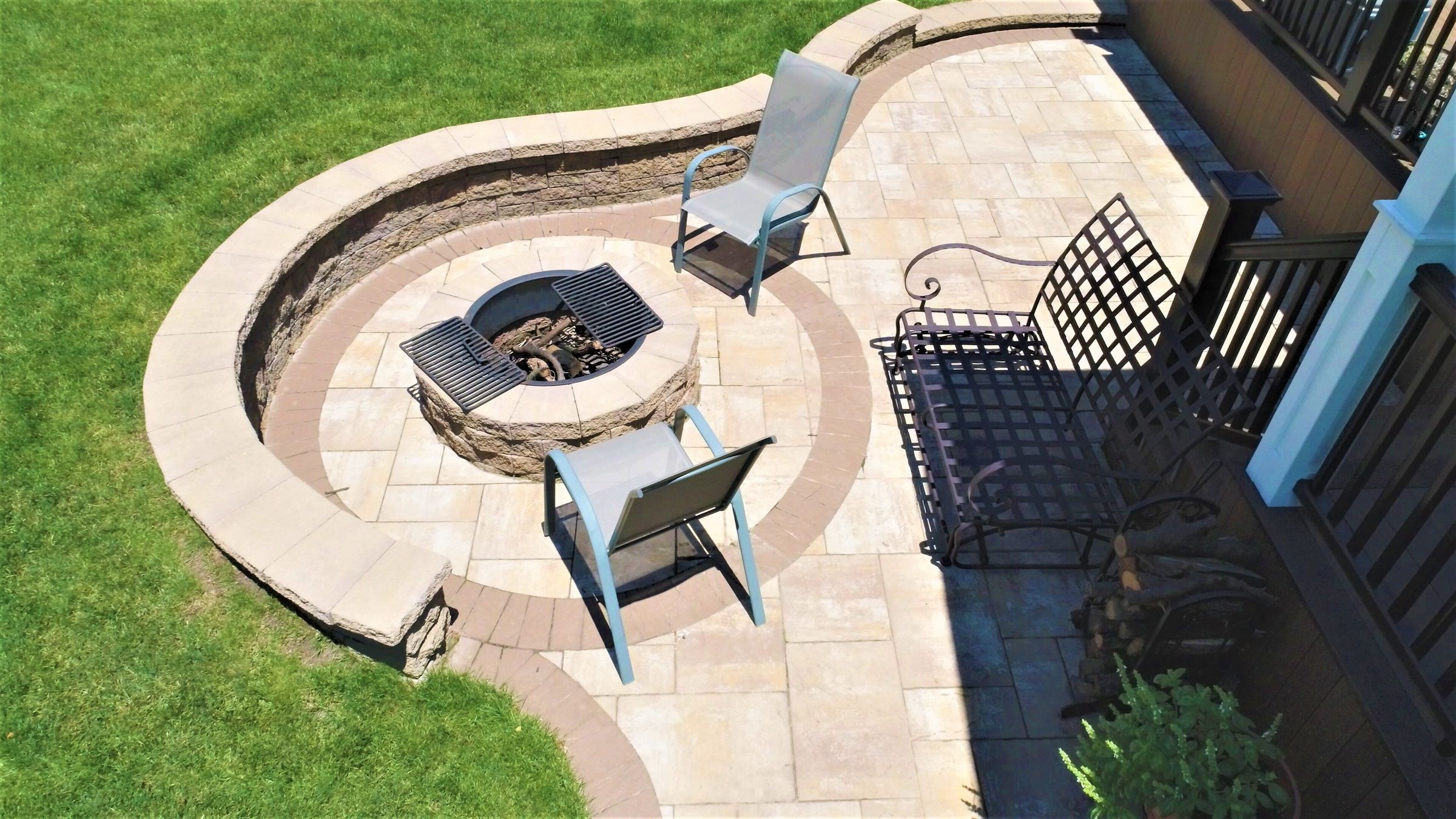 Paver patio with a round fire pit and curved seating wall