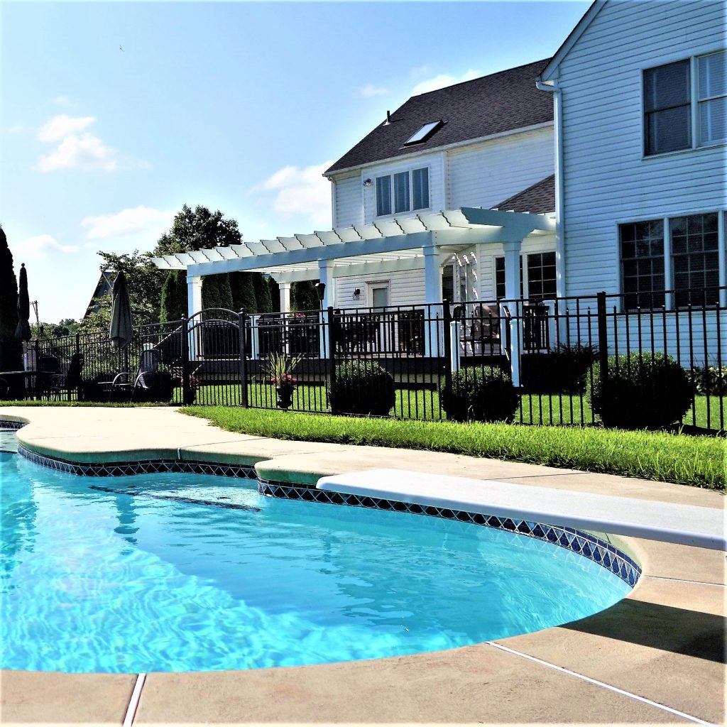 White pergola over a deck beside an inground pool